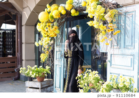A Muslim woman in a beautiful black outfit leaves the store covering her face 91110684