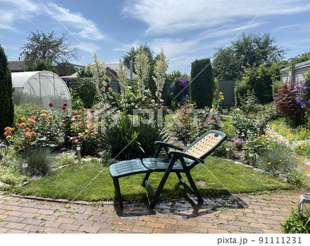 Backyard of house with flowers and garden recliner chair 91111231