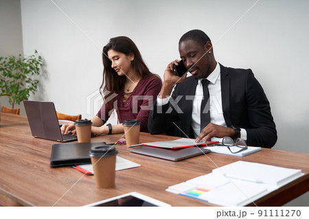 Young happy business people working together in modern office, multiethnic teamwork. Man calling with smartphone Young happy business people working together in modern office, multiethnic teamwork. Man calling with smartphone 91111270