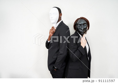 African man and Caucasian woman wearing black suits hiding face with plastic masks 91111597