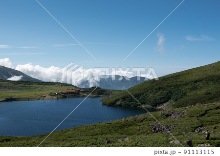 長野県富山県にある日本百名山の白馬岳への白馬大池付近の白馬大池山荘と雪渓と雲と青空の景色 長野県富山県にある日本百名山の白馬岳への白馬大池付近の白馬大池山荘と雪渓と雲と青空の景色 91113115
