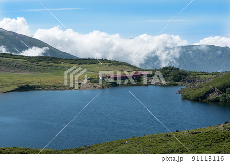 長野県富山県にある日本百名山の白馬岳への白馬大池付近の白馬大池山荘と雪渓と雲と青空の景色 長野県富山県にある日本百名山の白馬岳への白馬大池付近の白馬大池山荘と雪渓と雲と青空の景色 91113116