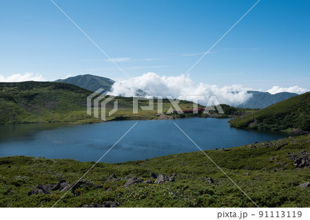 長野県富山県にある日本百名山の白馬岳への白馬大池付近の白馬大池山荘と雪渓と雲と青空の景色 長野県富山県にある日本百名山の白馬岳への白馬大池付近の白馬大池山荘と雪渓と雲と青空の景色 91113119