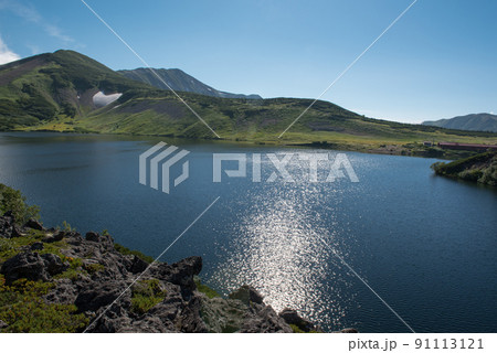 長野県富山県にある日本百名山の白馬岳への白馬大池付近の白馬大池山荘と雪渓と雲と青空の景色 91113121
