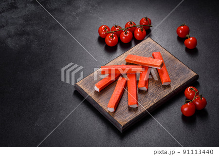 Crab sticks on a cutting Board with a knife. On black concrete background Crab sticks on a cutting Board with a knife. On black concrete background 91113440