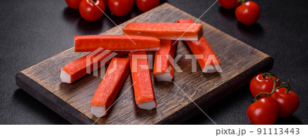 Crab sticks on a cutting Board with a knife. On black concrete background 91113443