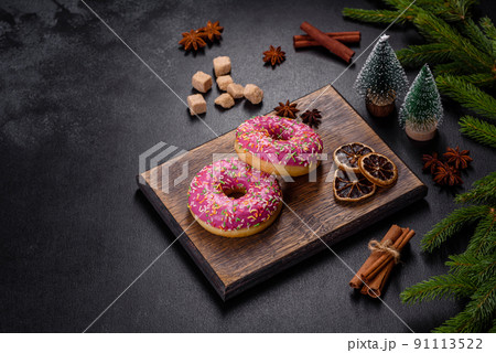 A beautiful doughnut with pink glaze and colored sprinkle on a christmas table 91113522