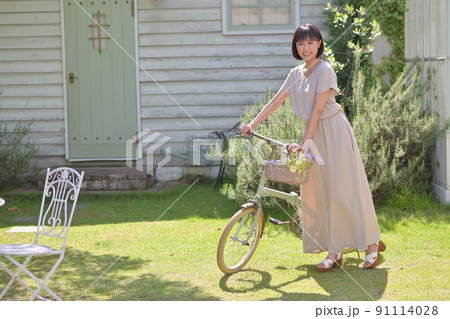 庭の芝の上で自転車をおす若い女性 91114028