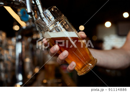 Pouring beer into a mug in a beer bar close-up. Beer bottling in the restaurant. The bar counter. Pouring beer into a mug in a beer bar close-up. Beer bottling in the restaurant. The bar counter. 91114886