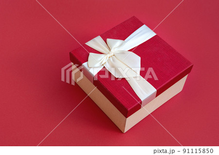 Top view of beautiful red gift box with satin light ribbon on red background. A gift for Christmas, New Year or a romantic Valentine's Day. Copy space for text. 91115850