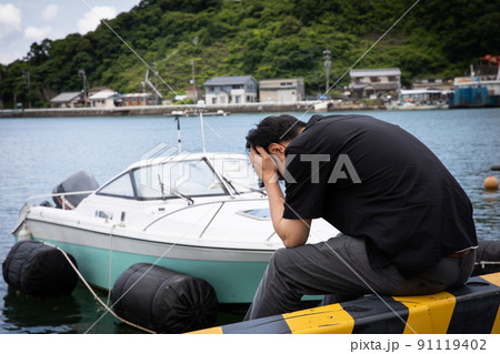 海辺で頭を抱える男性　Worried man 91119402
