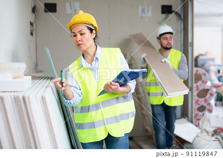Female building inspector taking inventory of materials at construction site Female building inspector taking inventory of materials at construction site 91119847