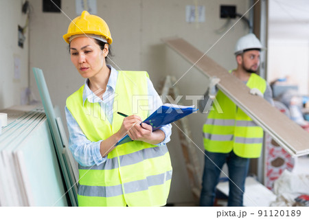 Female building inspector taking inventory of materials at construction site Female building inspector taking inventory of materials at construction site 91120189