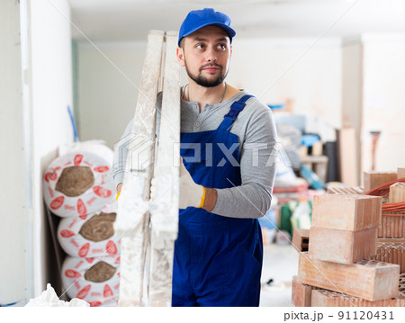 Construction worker carrying ladder at renovating object Construction worker carrying ladder at renovating object 91120431
