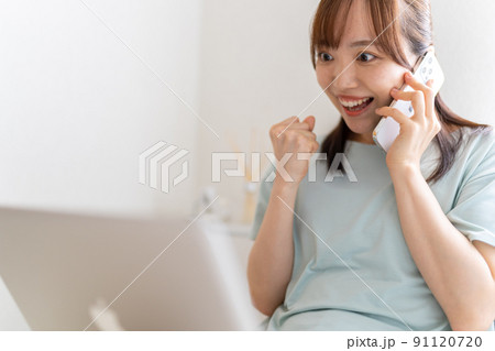 女性　スマホ　通話　ベッド　パソコン　ガッツポーズ 91120720