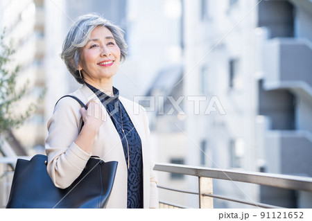 ビジネス街でバッグを持って立つミドル女性 91121652