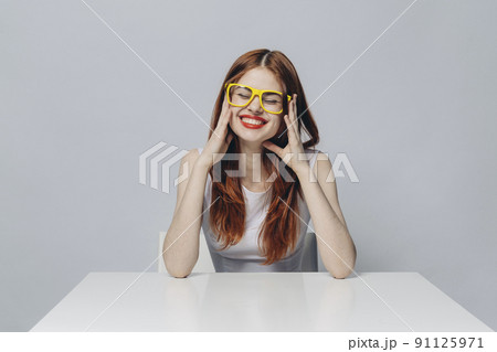 Laughing Caucasian woman sitting at table wearing yellow eyeglasses Laughing Caucasian woman sitting at table wearing yellow eyeglasses 91125971