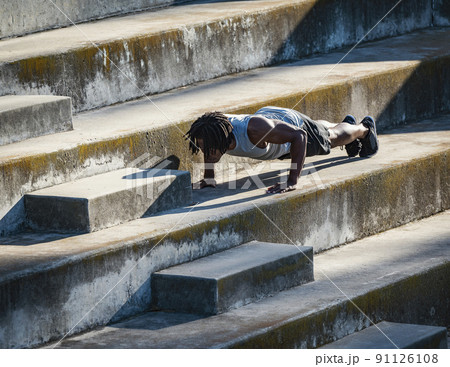 Athletic man doing push-ups on steps Athletic man doing push-ups on steps 91126108