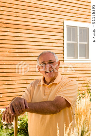 Senior man standing in front of house 91126395