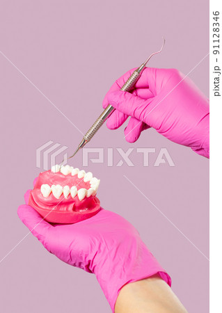 Dentist's hands with layout of the human jaw and dental restoration instrument. 91128346