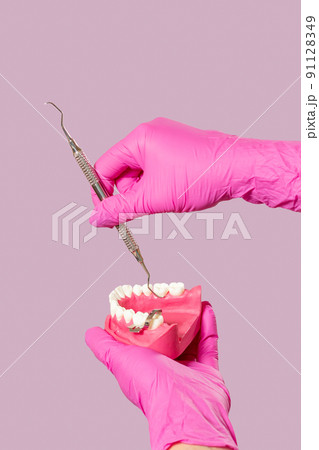 Dentist's hands with layout of the human jaw and dental restoration instrument. 91128349
