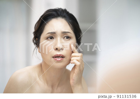 鏡に向かうアラフィフの女性　スキンケア　肌の悩み　イメージ 91131536