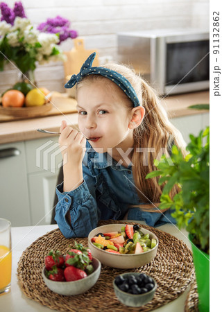Cute little girl eats fruit salad 91132862
