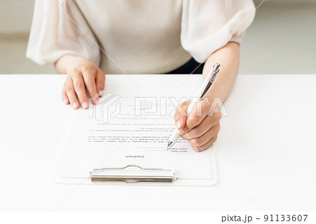 .書類にサインをしている女性の手元 91133607