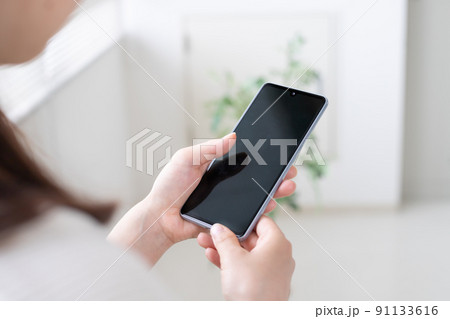 スマホやSNS運用をする女性の手元 91133616