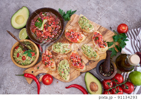 tasty salsa and guacamole bruschetta snacks at domestic kitchen on wooden cutting board 91134293
