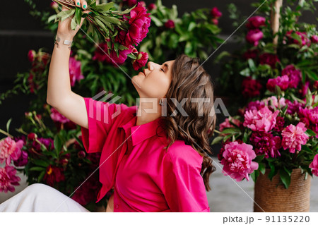 an attractive young woman in a pink blouse with peony flowers 91135220