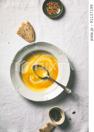 Empty plate of pumpkin soup on white tablecloth 91137199
