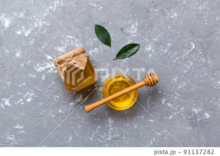 Honey jar with wooden honey dipper on white background top view with copy space. Delicious honey bottle 91137282