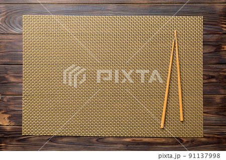 Two chopsticks and bamboo mat on wooden background. Top view, copy space Two chopsticks and bamboo mat on wooden background. Top view, copy space 91137998