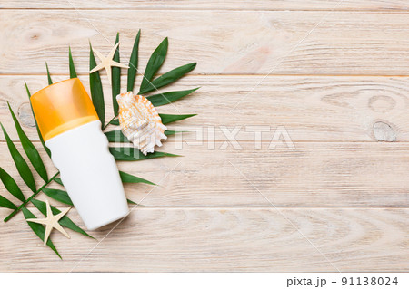 Sunscreen spray bottle. Bottle with sun protection cream and sea shells with tropical green leaf on color background, top view Sunscreen spray bottle. Bottle with sun protection cream and sea shells with tropical green leaf on color background, top view 91138024