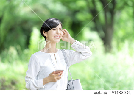 屋外でスマホを持つビジネスウーマン スマートフォンを持つ若い女性 屋外でスマホを持つビジネスウーマン スマートフォンを持つ若い女性 91138036