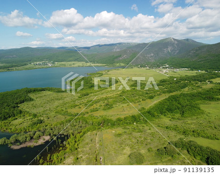 Aerial view on water reservoir at mountain valley covered with green spring forest. Beautiful view from above on smooth blue surface of mountain lake among highlands. Drone point of view. Nobody Aerial view on water reservoir at mountain valley covered with green spring forest. Beautiful view from above on smooth blue surface of mountain lake among highlands. Drone point of view. Nobody 91139135