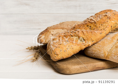 Freshly baked bread on cutting board against white wooden background. perspective view bread with copy space 91139291