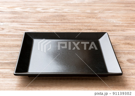 Perspective view of empty square plate on wooden background. Empty space for your design Perspective view of empty square plate on wooden background. Empty space for your design 91139302