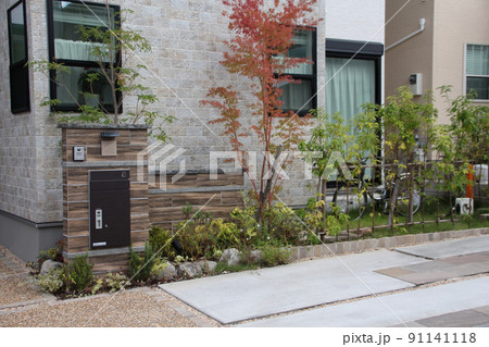 紅葉が美しく映える落ち着いた雰囲気の木目調タイル張りが品のある戸建て住宅の門柱と庭園 91141118