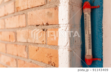 thermometer hangs on the window near the brick wall. Picture for hardware store, home advertising equipment, agriculture book. 91143409