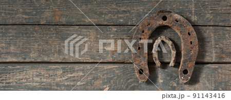 Old rusty horseshoe and small goat horseshoe on a wooden background. 91143416