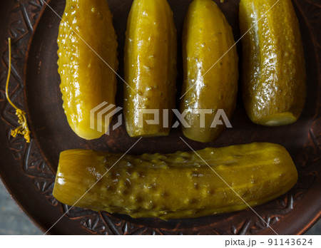 Salted pickled cucumbers on a brown plate on a wooden texture Salted pickled cucumbers on a brown plate on a wooden texture 91143624