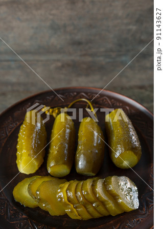 Salted pickled cucumbers on a brown plate on a wooden texture Salted pickled cucumbers on a brown plate on a wooden texture 91143627