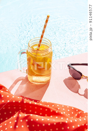 Cold drink on a hot summer day. Cocktail glass near swimming pool over blue sky background. Vacation, happiness, summer vibes and ad concept. Retro style 91146577