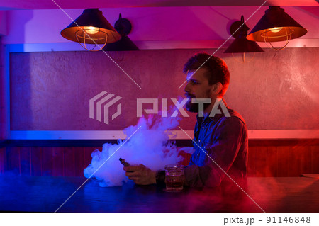 The man smoke an electronic cigarette at the vape shop. The man smoke an electronic cigarette at the vape shop. 91146848
