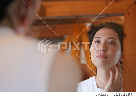 鏡を見て顔のむくみを気にする女性 91152294