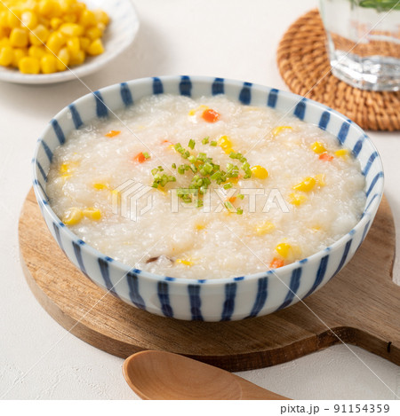 Delicious rice porridge congee with corn kernel and vegetables on white table background. 91154359