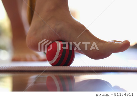 Person rolls massage ball with foot of foot closeup 91154911