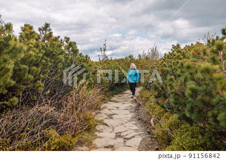 Portrait of a beautiful 50s blonde woman with a backpack in the mountains. Banner of hiker on adventure trek. 91156842